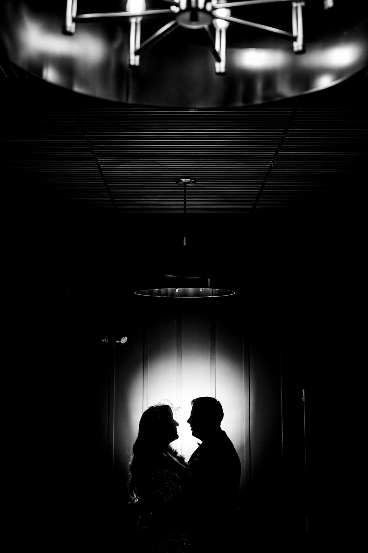 Black and white silhouette of a couple against a softly lit wall