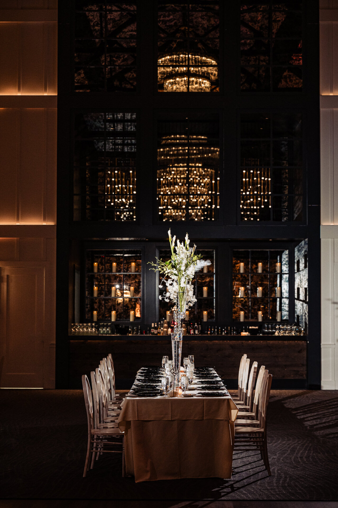 Elegant wedding reception table with tall floral centerpiece and dim lighting