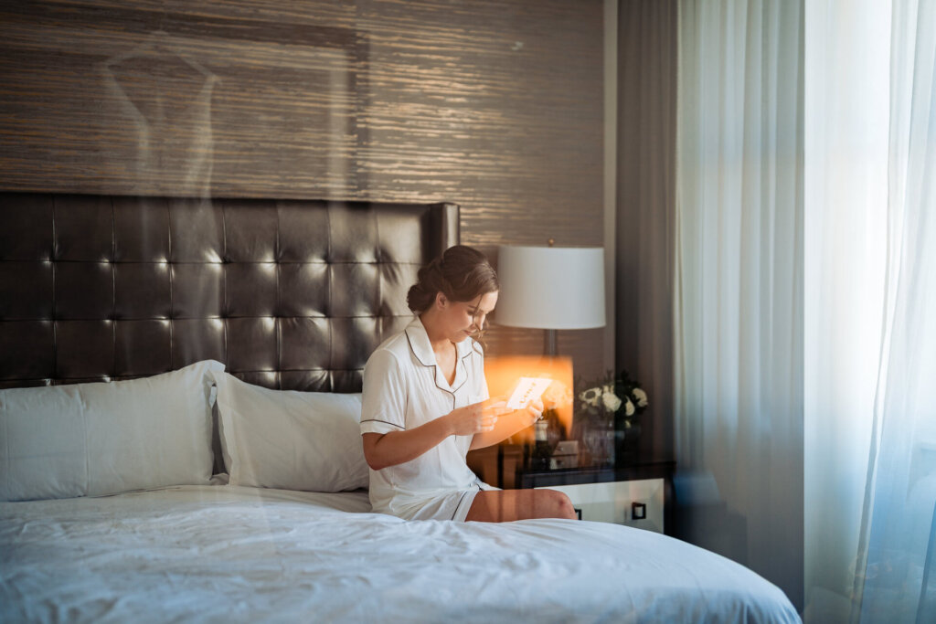 A quiet, emotional moment as the bride sits on the bed reading a handwritten note.