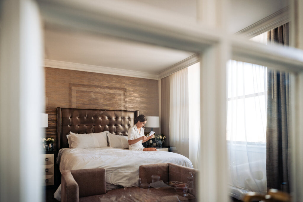 A quiet, emotional moment as the bride sits on the bed reading a handwritten note.
