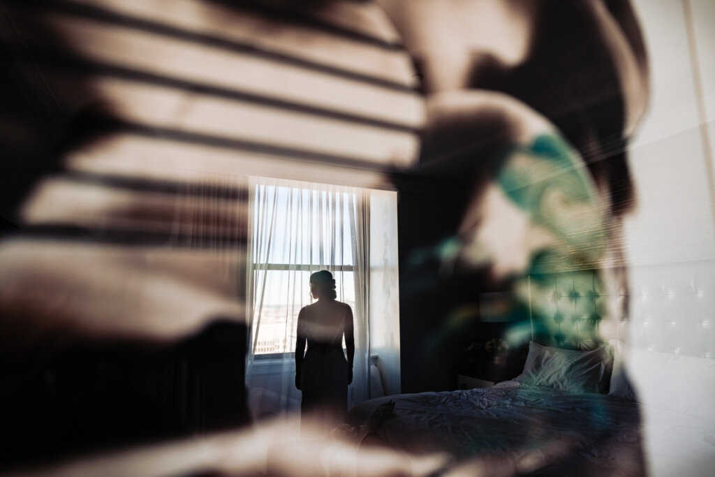 A dramatic, artistic shot of the bride framed by architectural shadows, adding depth to the image.
