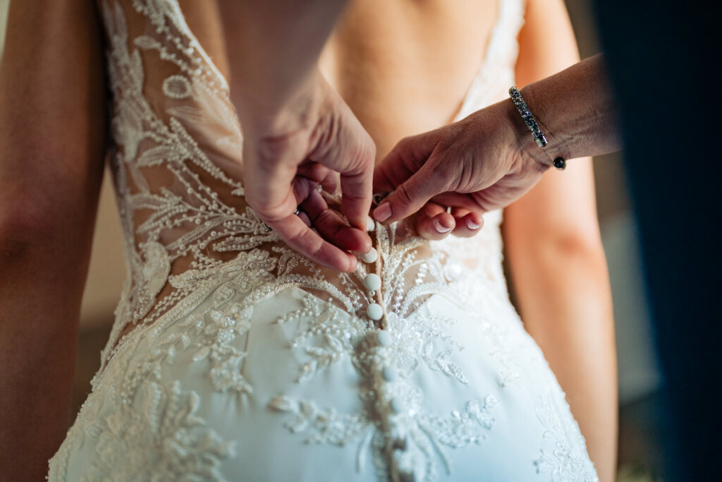 A close-up shot of a delicate buttoned back on a lace wedding dress.