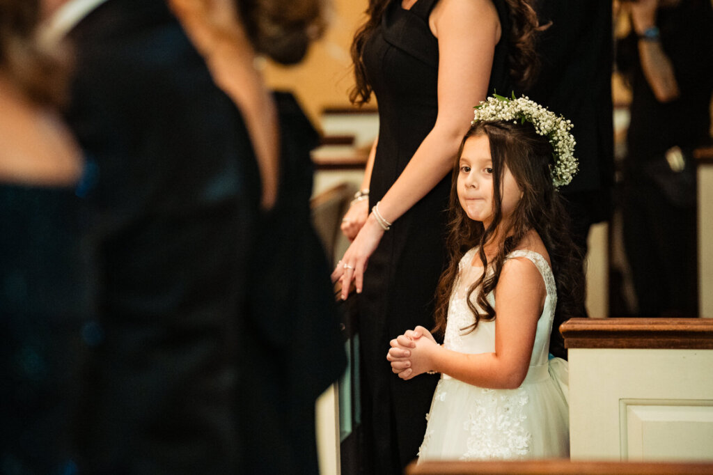 A sweet moment as a young flower girl stands with her hands clasped, watching the ceremony unfold.