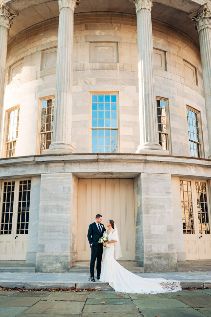 A timeless portrait of the couple posing at a historic venue with tall stone columns.