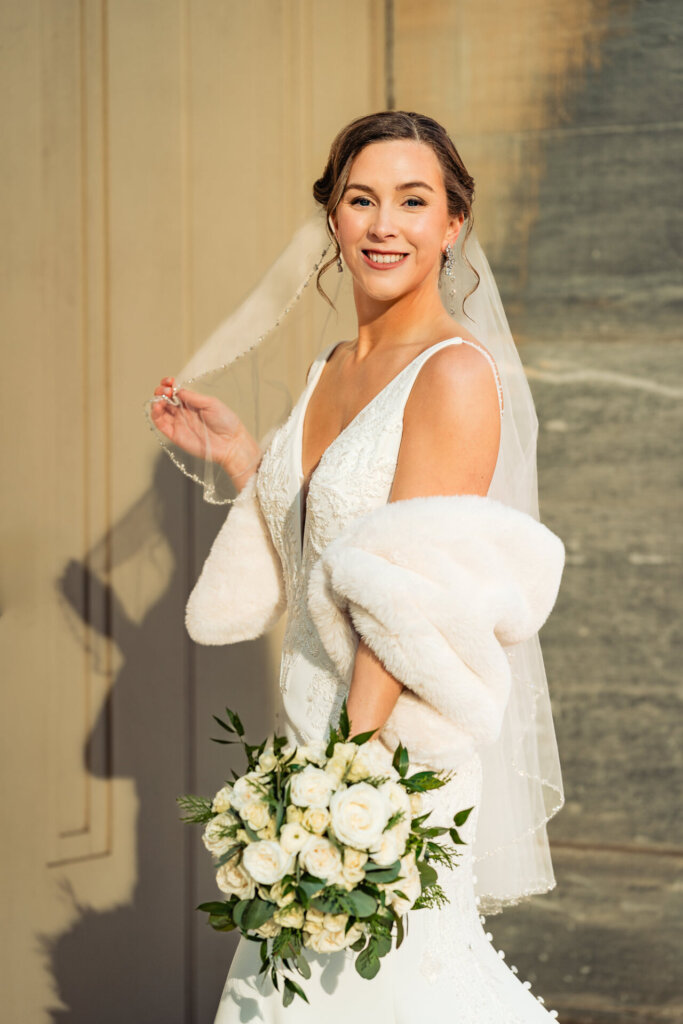 A radiant bride playfully lifting her veil, her expression full of excitement and happiness.