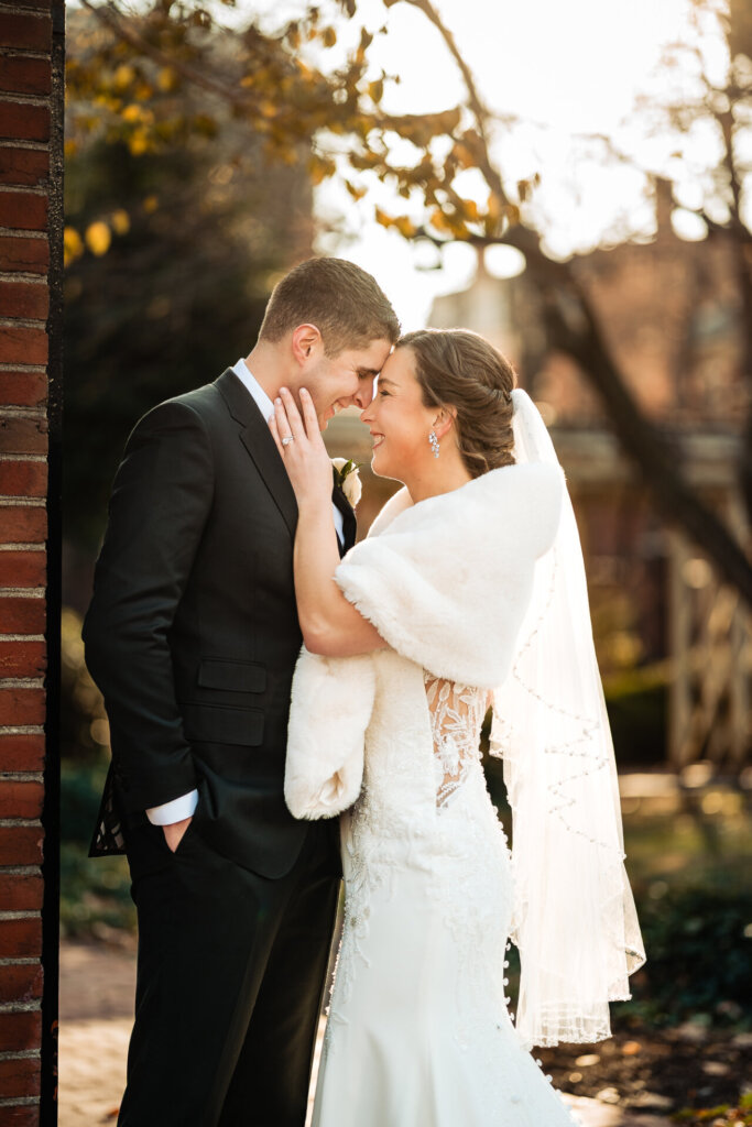 A warm embrace as the groom holds his bride close, with golden light filtering through the trees.