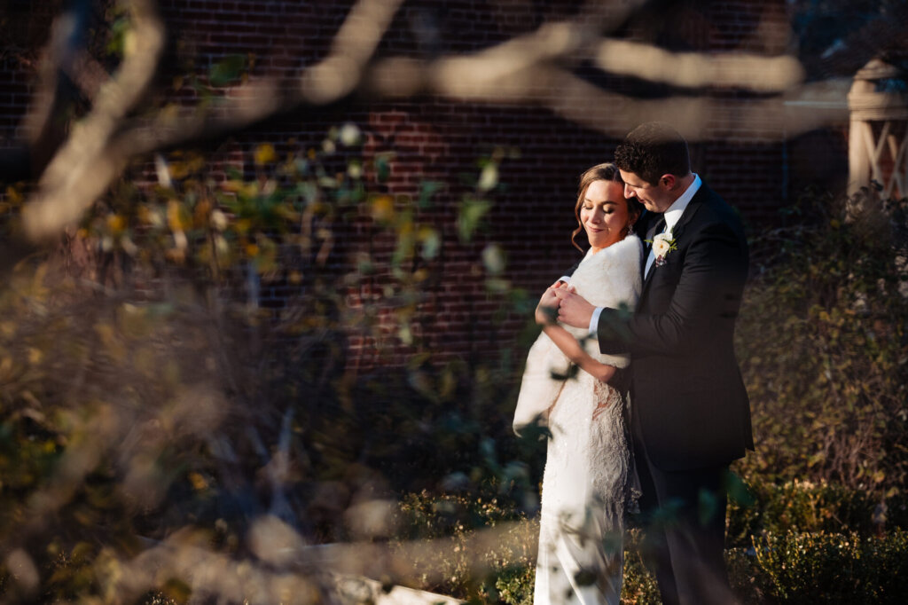 A soft-focus shot of the couple sharing an intimate embrace, framed by nature.