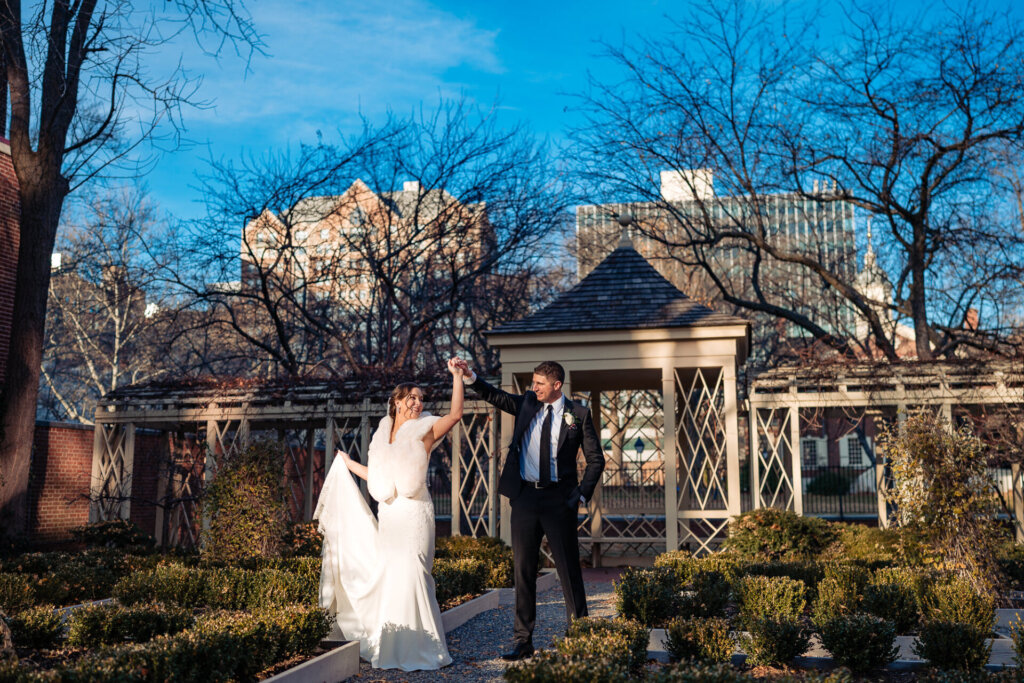 A joyful moment as the newlyweds share a playful dance in a lush courtyard.