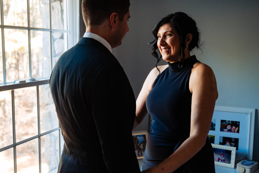 The groom and his mother stand together, exchanging a warm, emotional glance before the wedding.