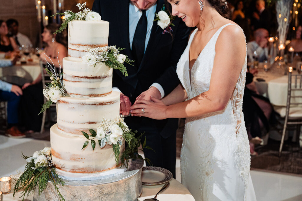 A candid moment as the newlyweds slice into their beautifully decorated wedding cake.